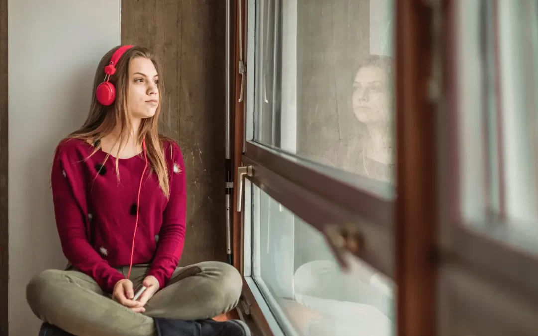 Teenage Marketing - Image of a teenager sitting on a window ledge with headphones on.